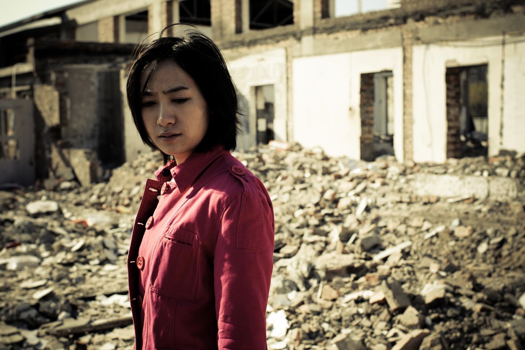 Image of woman surrounded by collapsed building structure after an earthquake.