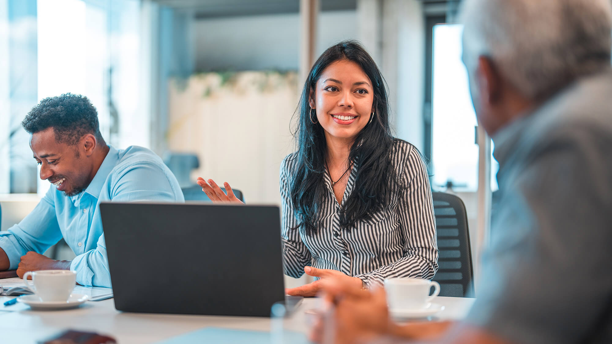 Woman in front of a laptop in a meeting room smiling at coworker